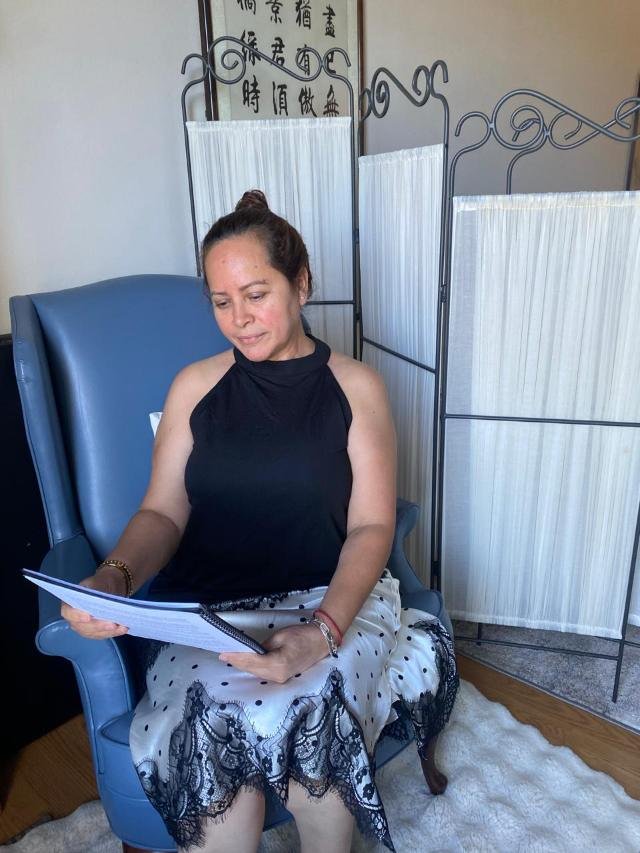 Alma sentada en un sillón azul, leyendo unas notas junto a una ventana